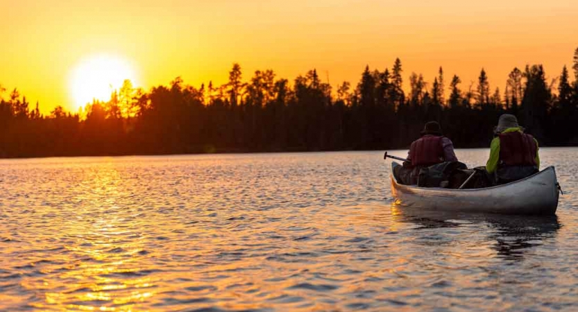 a canoe is paddled into the sunset by two students on an outward bound gap year expedition 